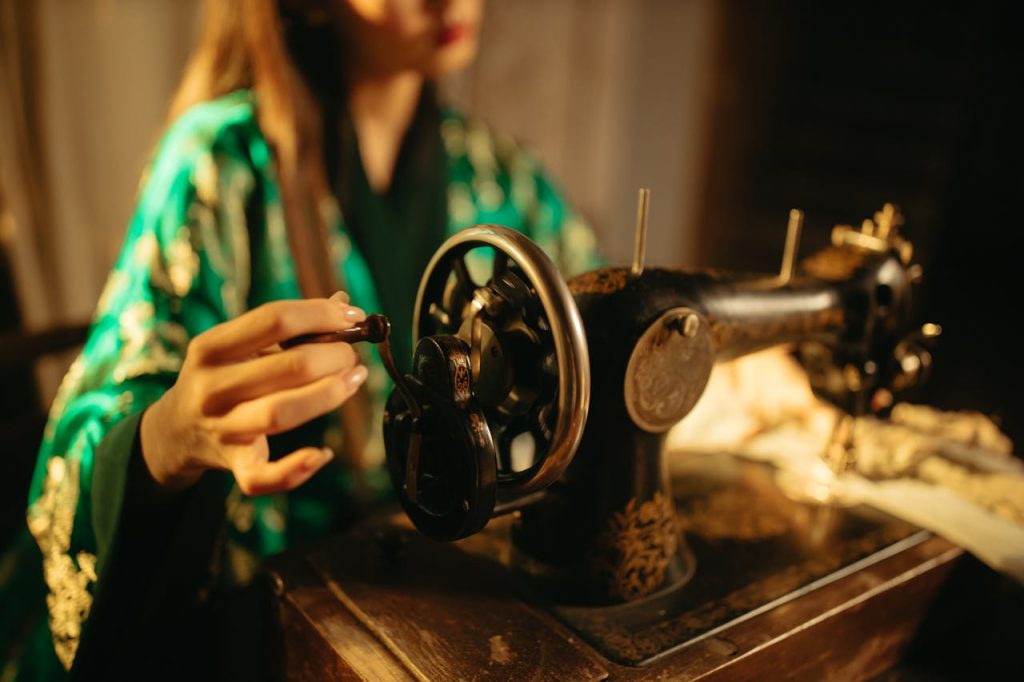 Woman in kimono using vintage sewing machine in a cozy workshop setting.